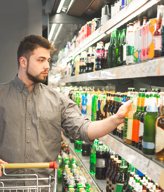 Shopper choosing a bottled drink from a supermarket beverage aisle